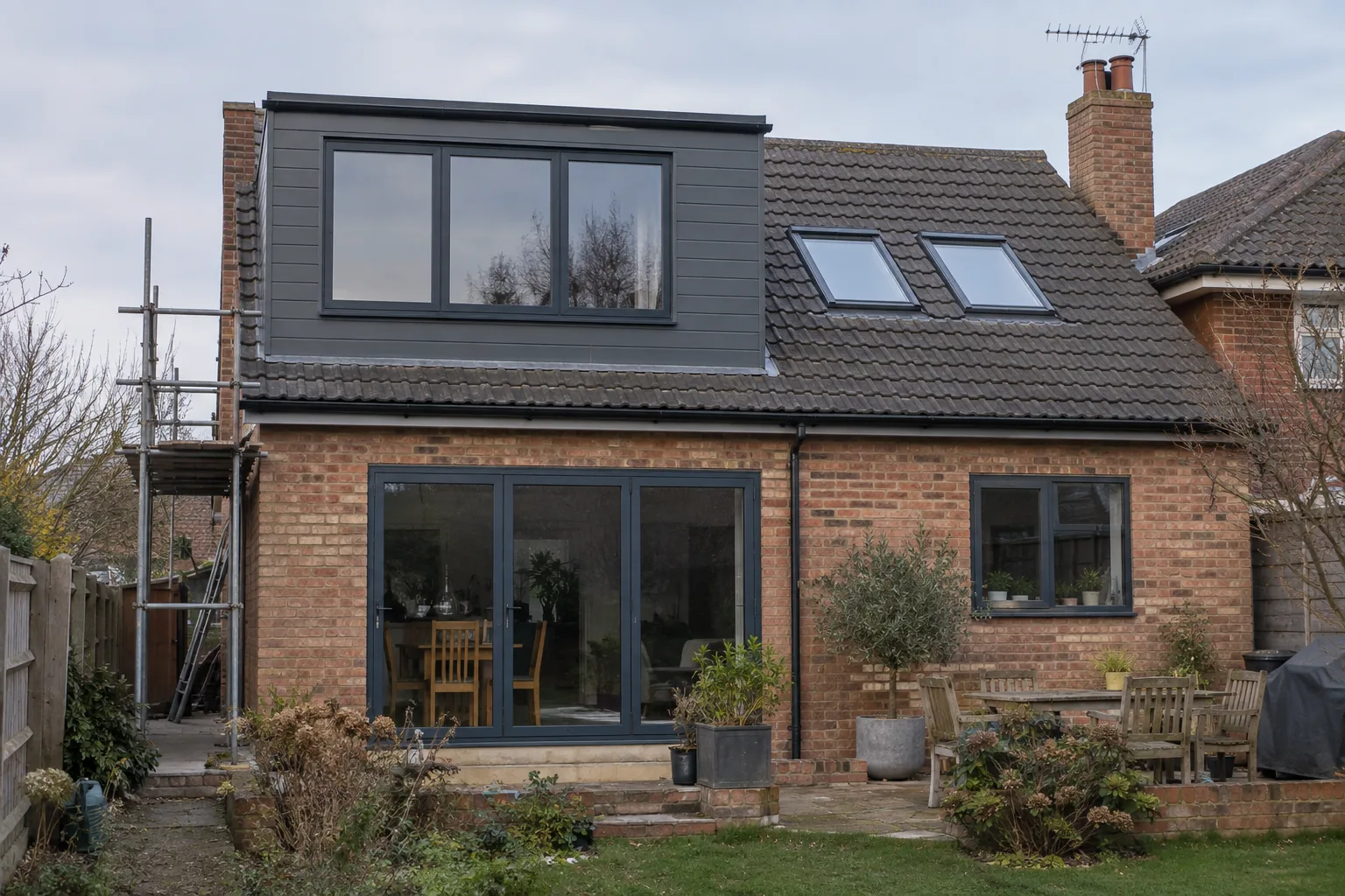 A grey-clad rear dormer with anthracite windows beside two roof windows.