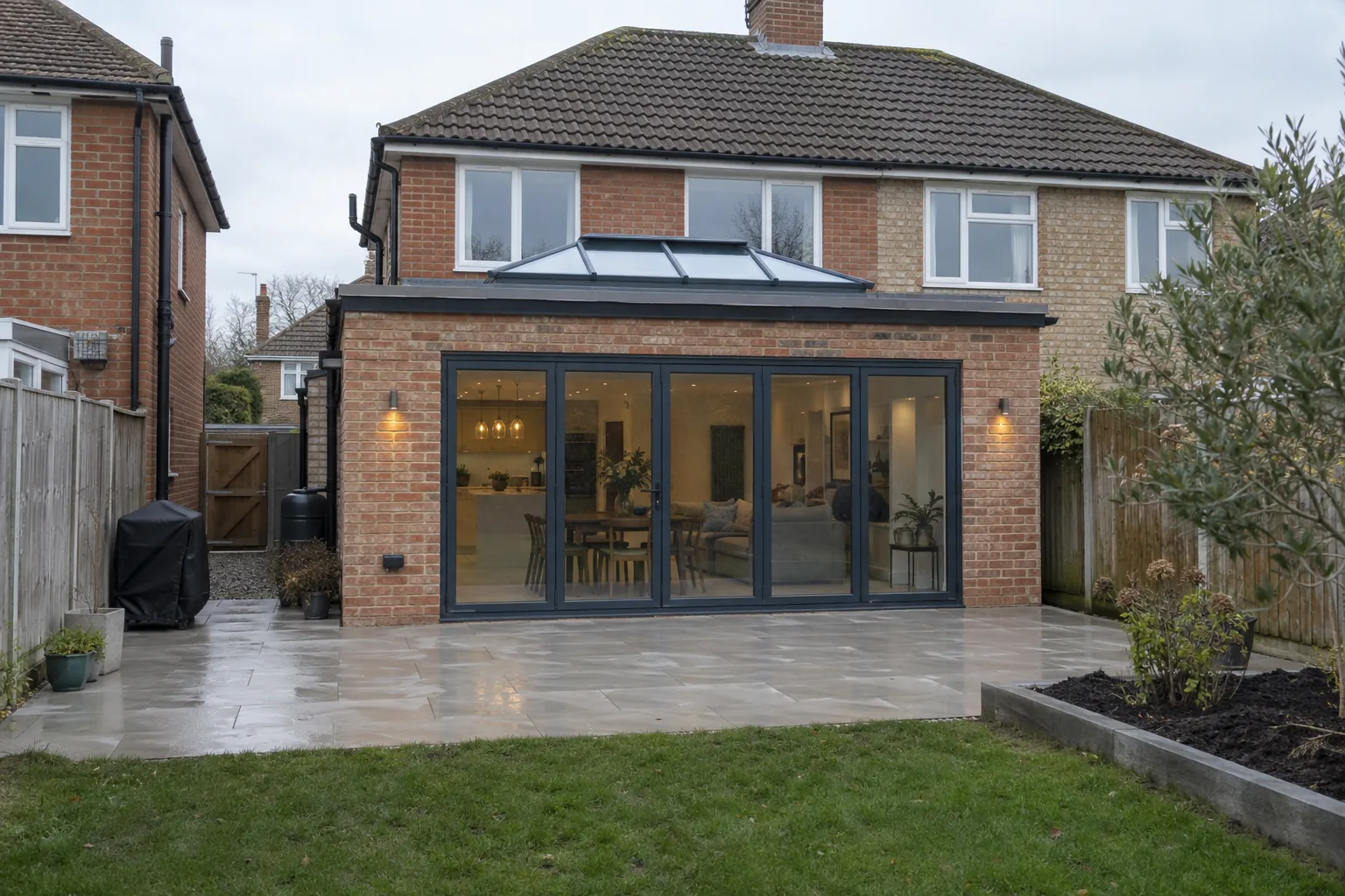 A brick rear extension with anthracite bi-fold doors, a roof lantern and a porcelain patio.